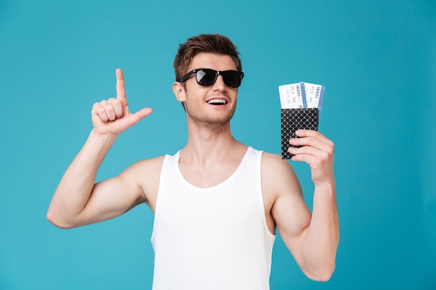 Homem de óculos escuros segurando pasport com bilhetes