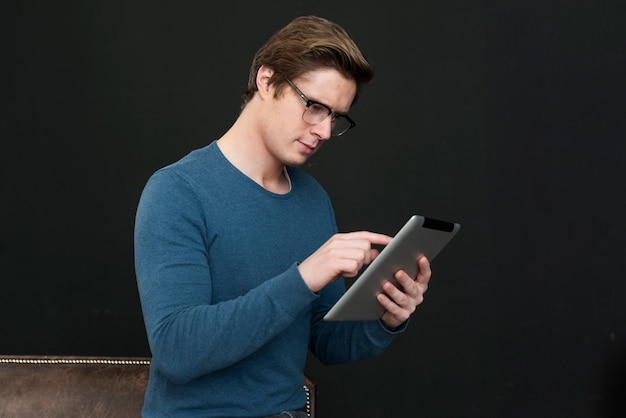 Homem de óculos olhando no tablet