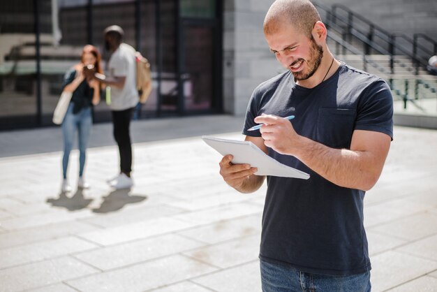 Homem de pé fora mantendo o bloco de notas sorrindo