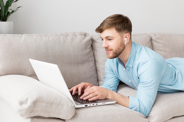 Homem de retrato deitado no sofá com o laptop