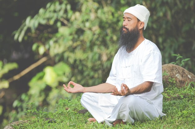 Homem de roupa branca meditando na natureza