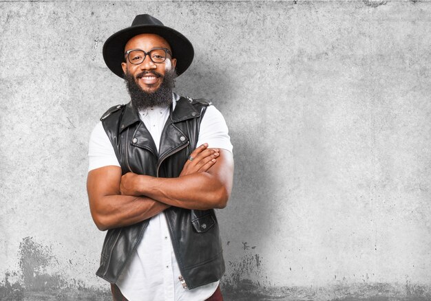 Homem de sorriso com um chapéu e os braços cruzados