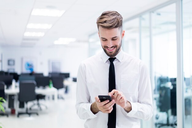 Homem de sorriso que datilografa em seu telefone