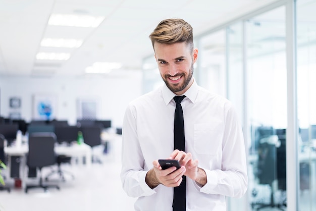 Homem de sorriso que datilografa em um celular