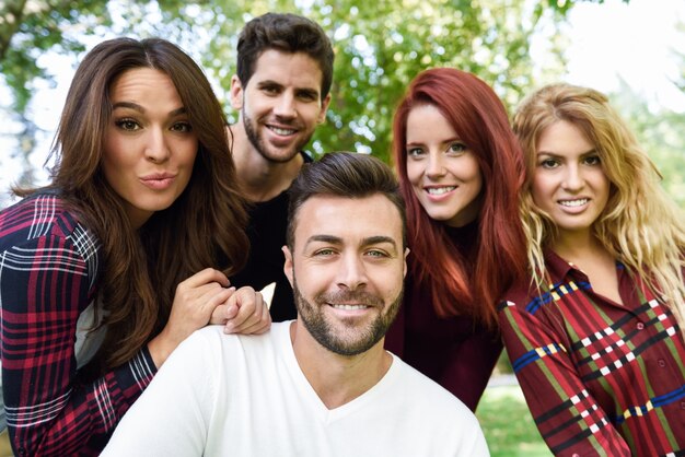 Homem de sorriso que toma um self foto dele e de seus amigos com as árvores no fundo