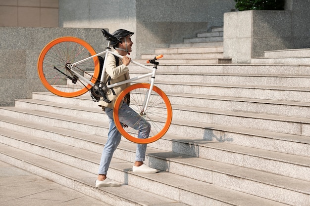 Foto grátis homem de tiro completo carregando bicicleta nas escadas