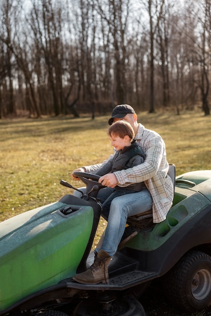 Homem de tiro completo com criança dirigindo cortador de grama