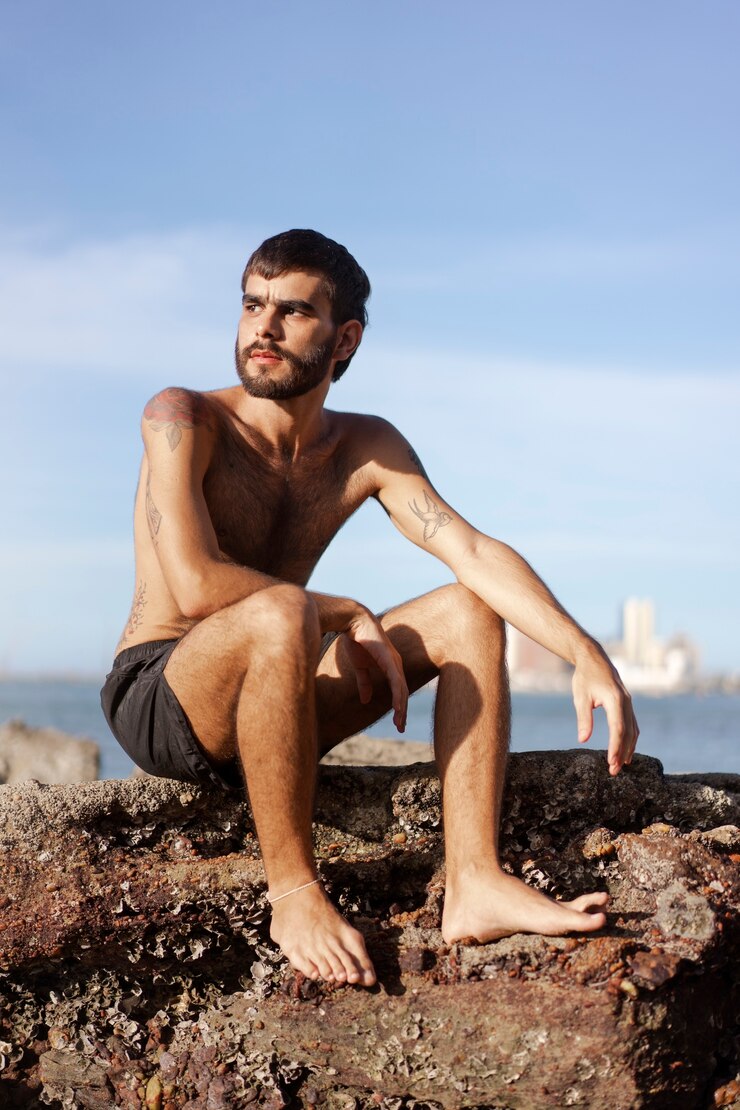 Foto grátis homem de tiro completo com peito peludo à beira-mar