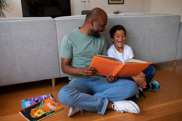 Homem de tiro completo e menino lendo quadrinhos em casa