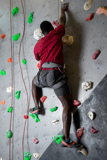 Foto grátis homem de tiro completo escalando a parede