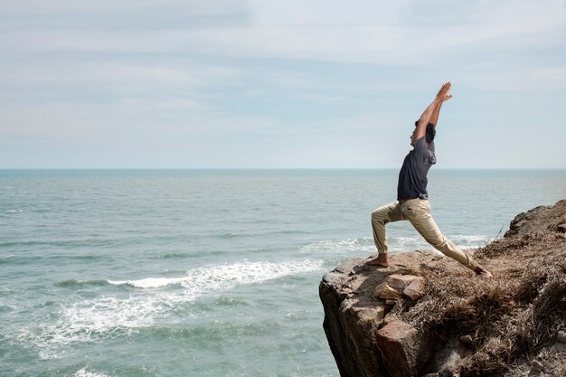 Homem de tiro completo fazendo ioga à beira-mar