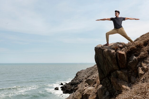 Homem de tiro completo fazendo ioga nas rochas