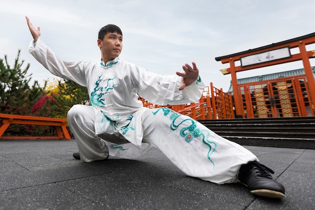 Homem de tiro completo praticando tai chi ao ar livre