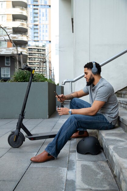 Homem de tiro completo sentado na escada com fones de ouvido