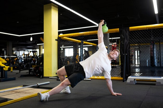 Homem de tiro completo treinando com kettlebell verde