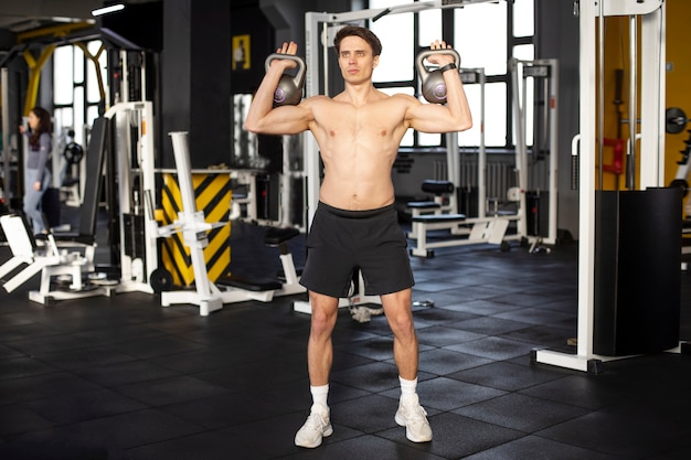 Homem de tiro completo treinando com kettlebells