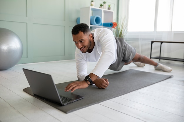 Homem de tiro completo treinando com laptop