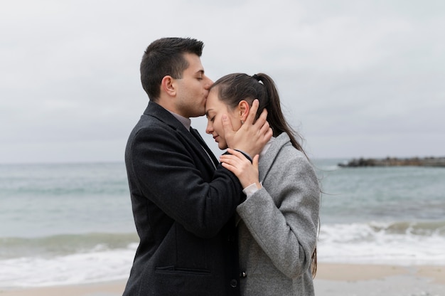 Homem de tiro médio beijando a testa da mulher