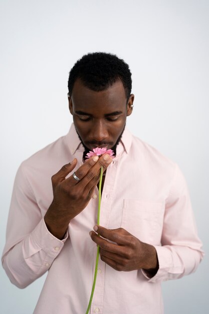 Homem de tiro médio cheirando a flor