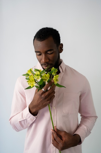 Foto grátis homem de tiro médio cheirando flores