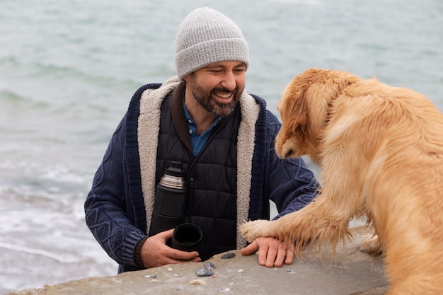 Foto grátis homem de tiro médio com cachorro à beira-mar