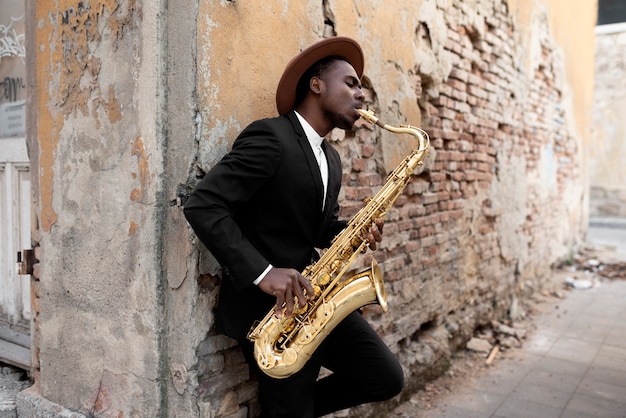 Homem de tiro médio com chapéu tocando saxofone