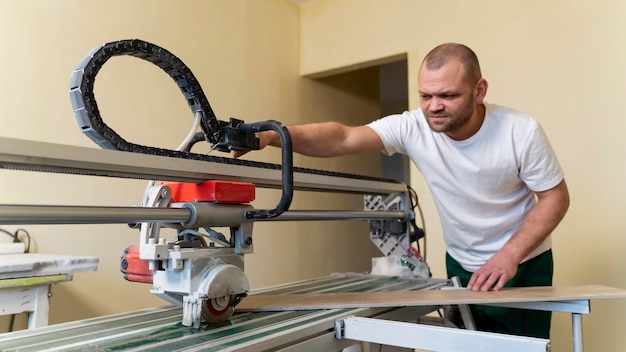 Homem de tiro médio cortando telha com máquina