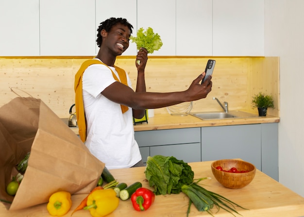 Homem de tiro médio cozinhando com smartphone