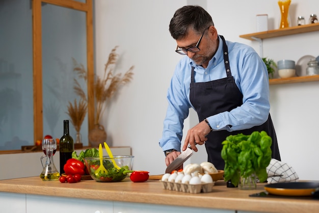 Foto grátis homem de tiro médio cozinhando na cozinha