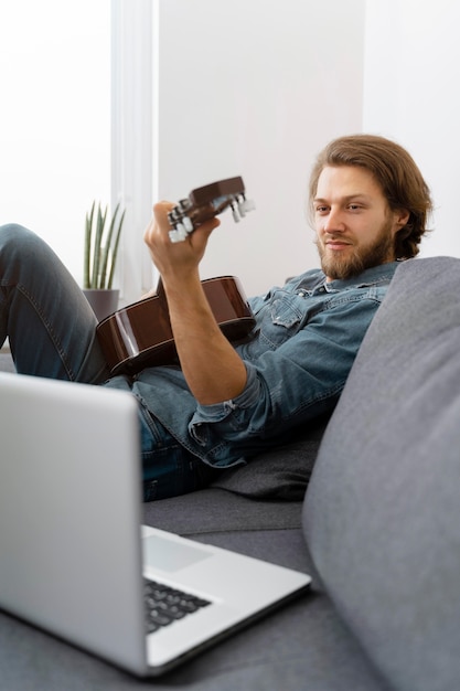 Homem de tiro médio em casa com violão