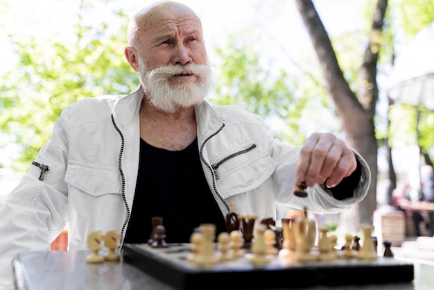 Homem de tiro médio jogando xadrez ao ar livre