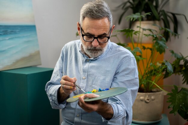 Homem de tiro médio pintando aquarelas