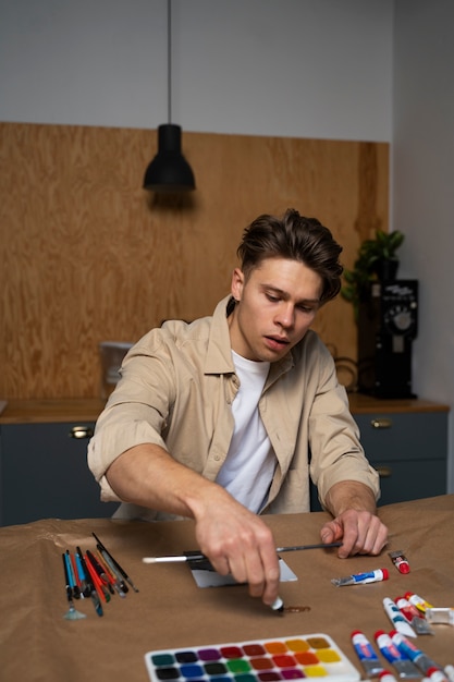 Foto grátis homem de tiro médio pintando aquarelas