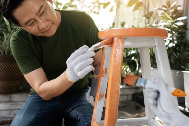 Homem de tiro médio pintando cadeira de madeira