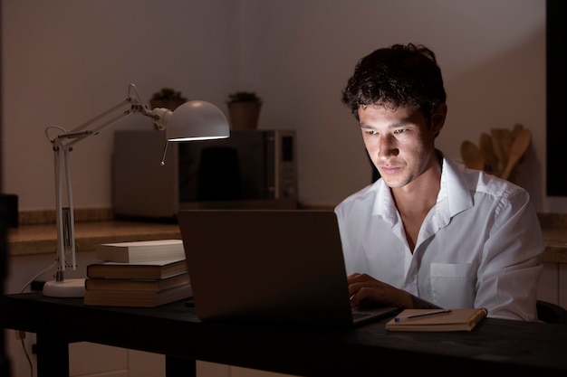 Homem de tiro médio sentado à mesa com um laptop