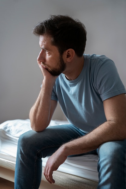 Homem de tiro médio sentado na cama