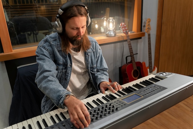 Foto grátis homem de tiro médio tocando piano no estúdio