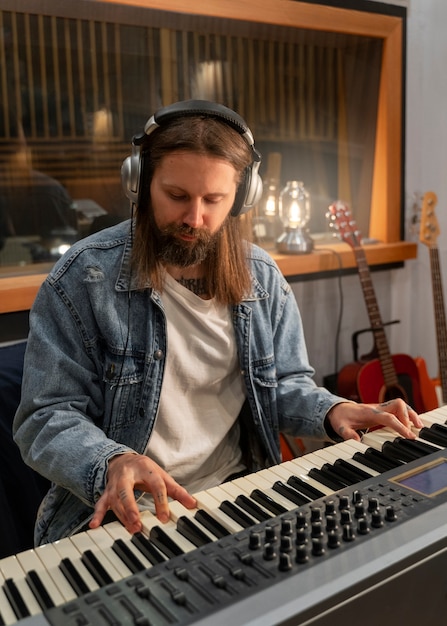 Foto grátis homem de tiro médio tocando piano no estúdio