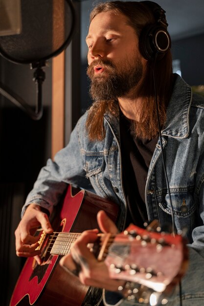 Homem de tiro médio tocando violão no estúdio