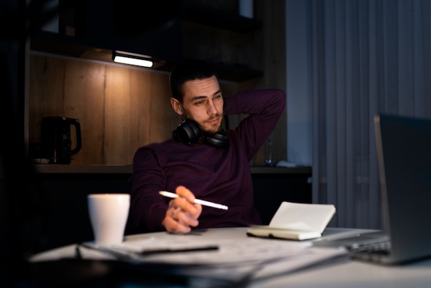 Homem de tiro médio trabalhando tarde da noite no laptop