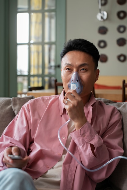 Foto grátis homem de tiro médio usando nebulizador em casa