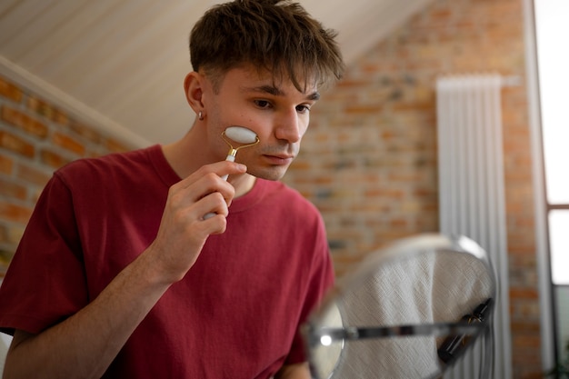 Foto grátis homem de tiro médio usando rolo facial para massagem