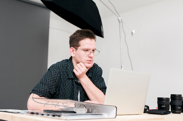 Homem de trabalho fotógrafo olhando para seu laptop