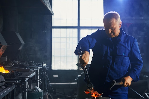 Foto grátis homem de uniforme azul escuro trabalhando com martelo e alicate