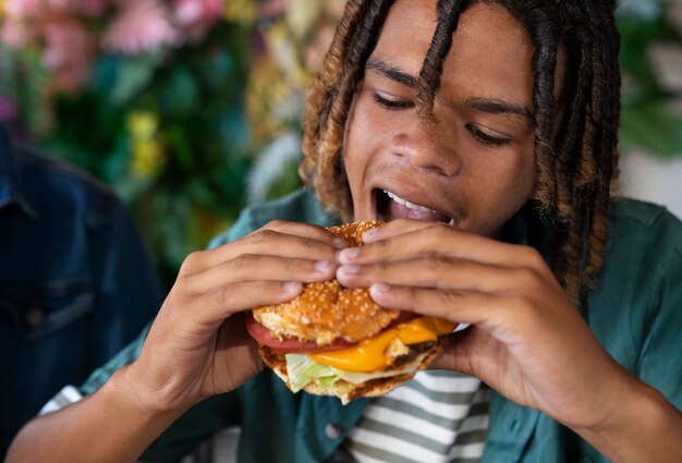 Homem de vista frontal comendo hambúrguer de uma forma engraçada