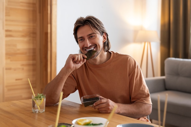 Foto grátis homem de vista frontal comendo lanches de algas marinhas