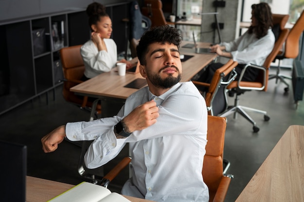 Foto grátis homem de vista frontal se alongando no trabalho