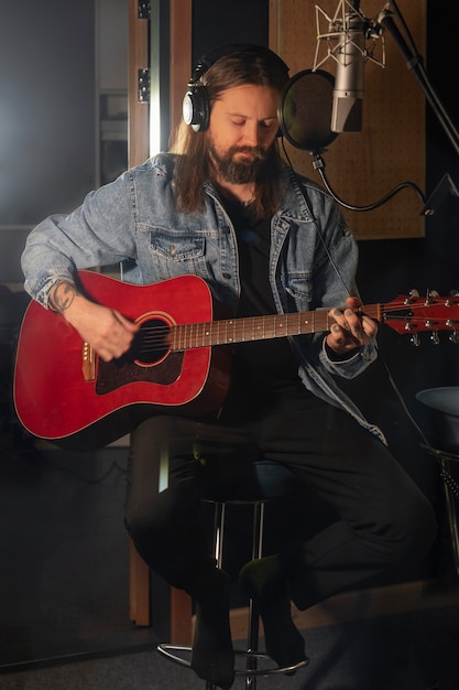 Homem de vista frontal tocando violão no estúdio
