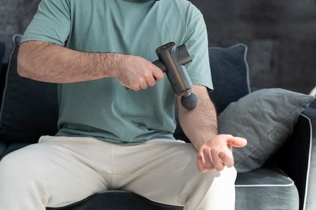 Foto grátis homem de vista frontal usando pistola de massagem