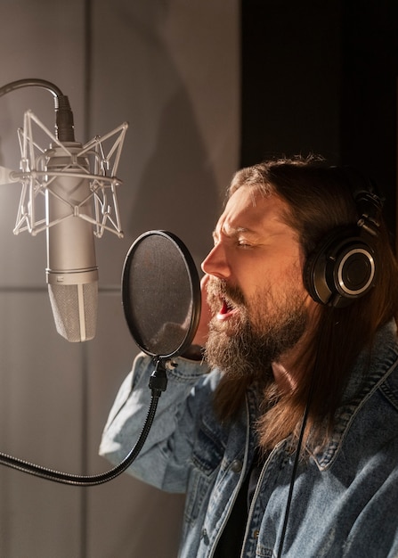 Foto grátis homem de vista lateral cantando no estúdio